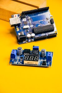 Close-up of an Arduino circuit board and sensor module on a bright yellow background.